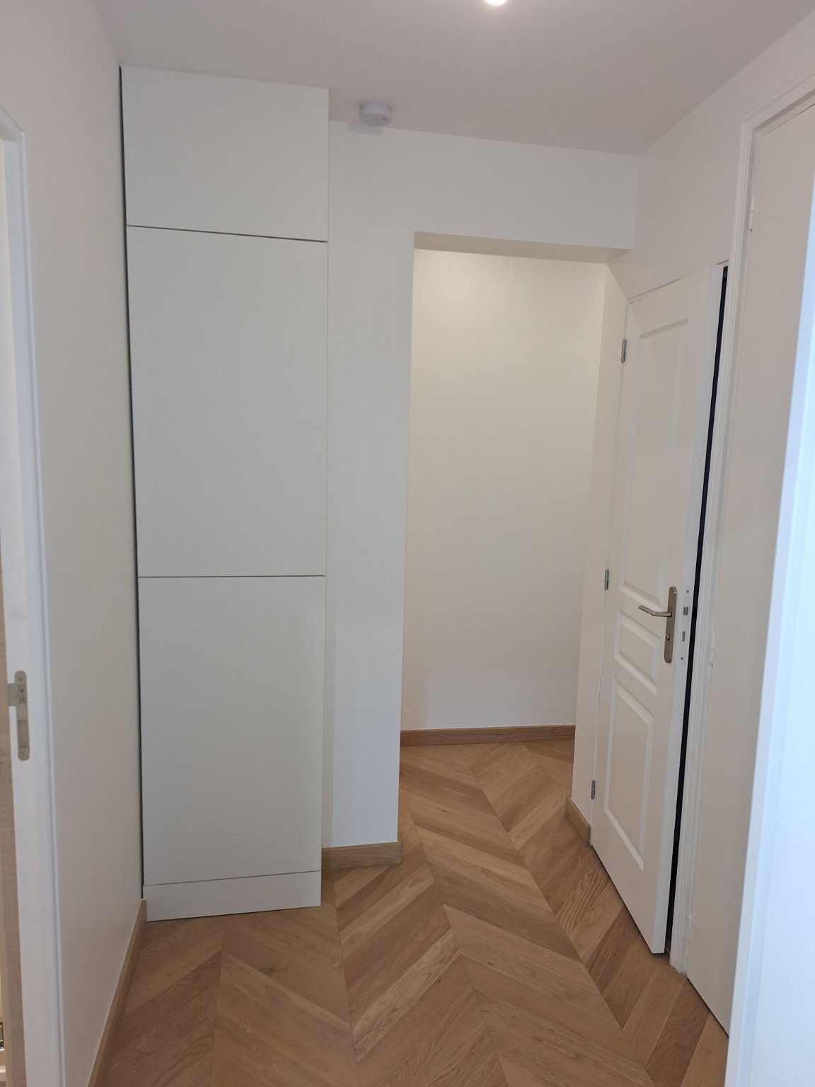 Couloir rénové avec parquet en chevrons et placard intégré