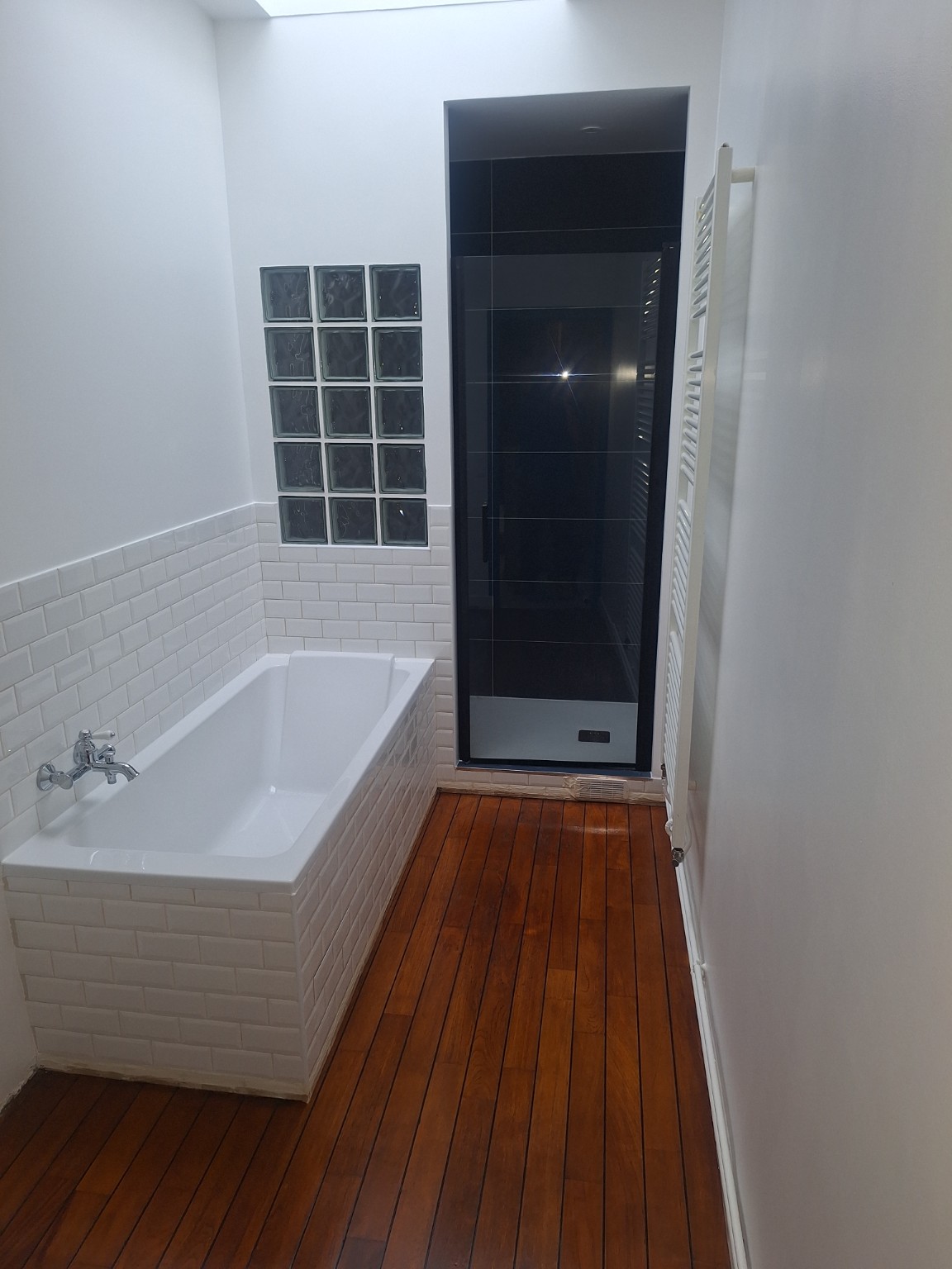 Salle de bains rénovée avec baignoire et sol en bois