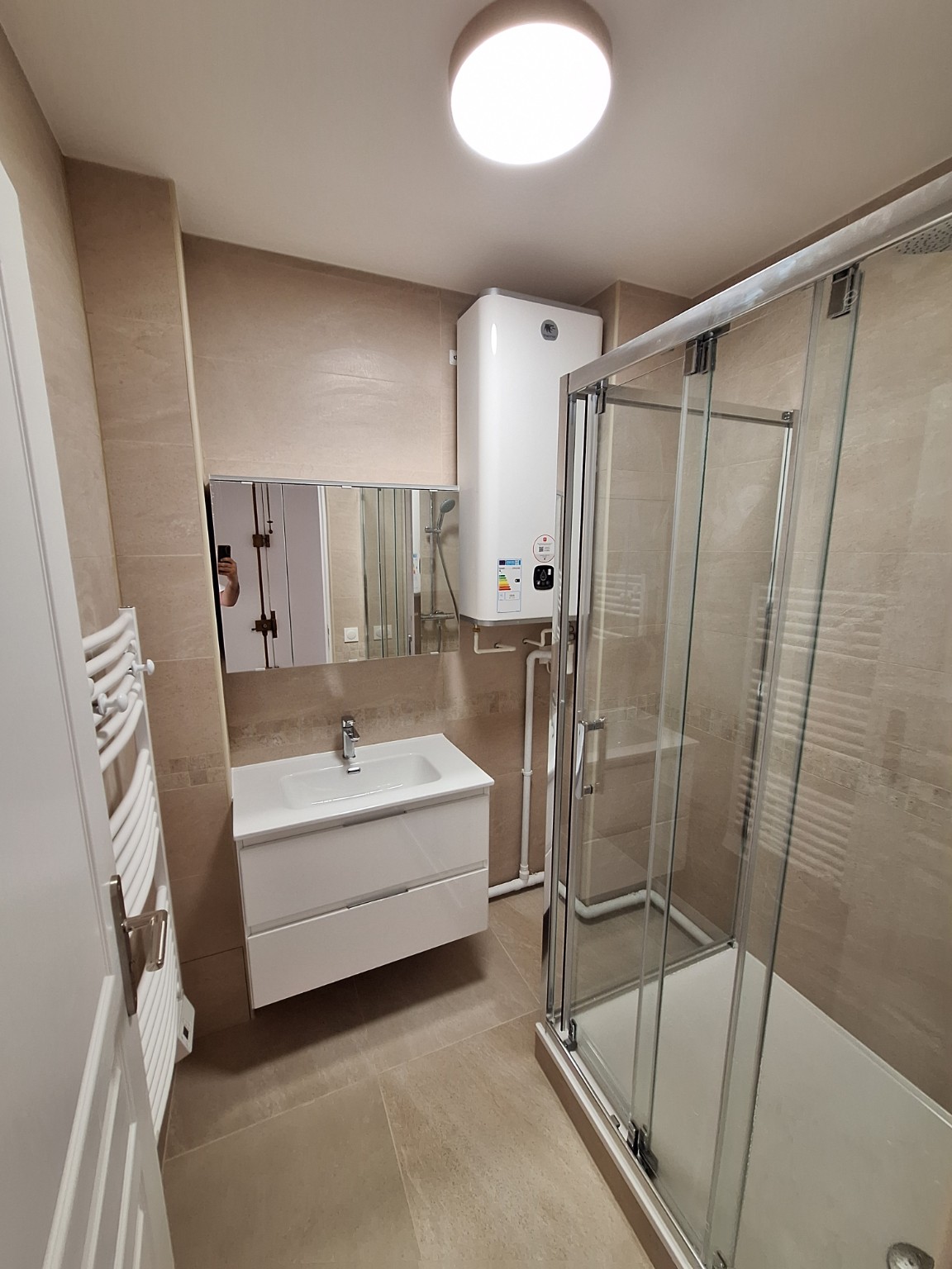 Salle de bains beige avec douche vitrée et meuble vasque