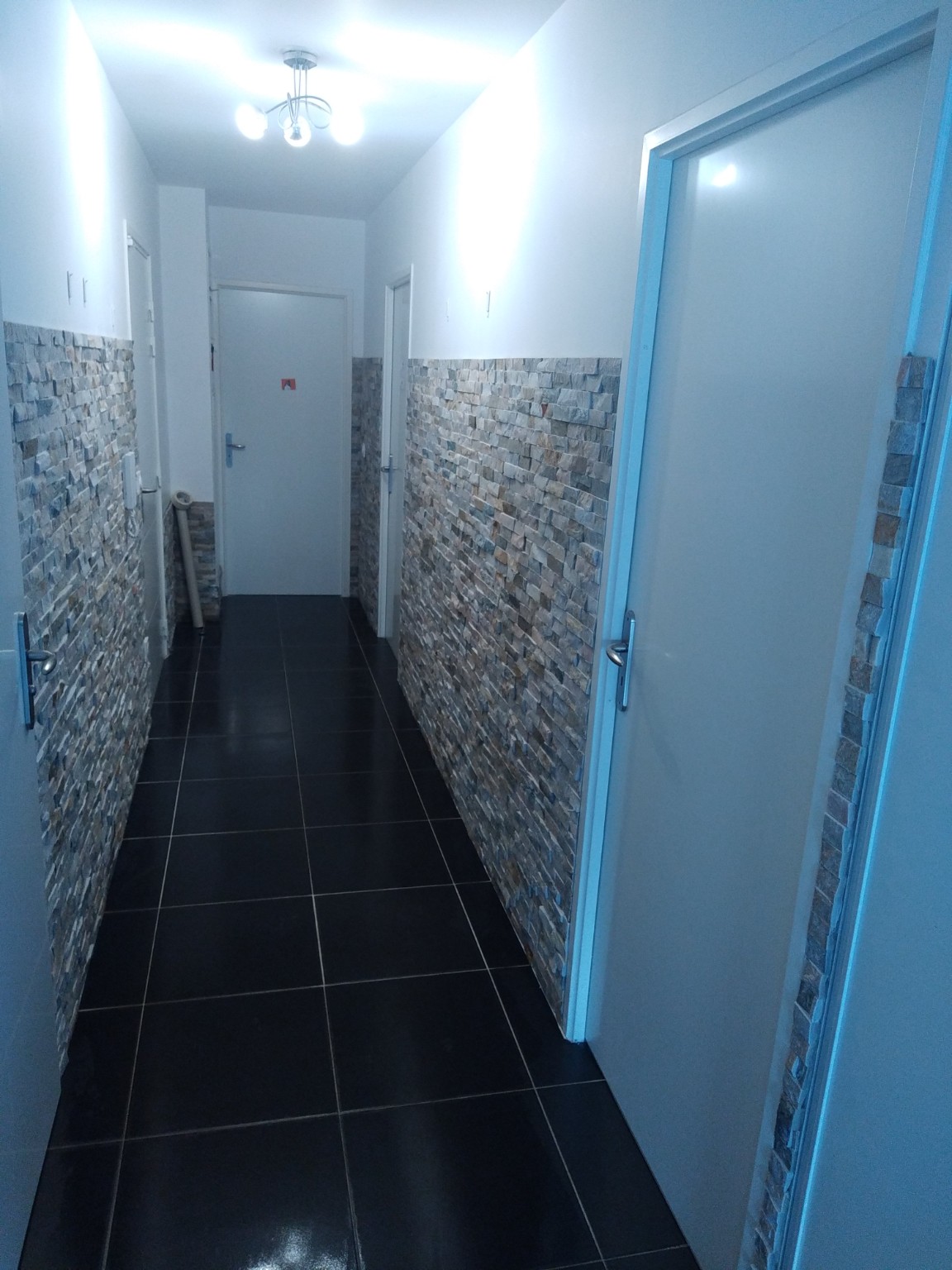 Couloir rénové avec carrelage mural et sol sombre