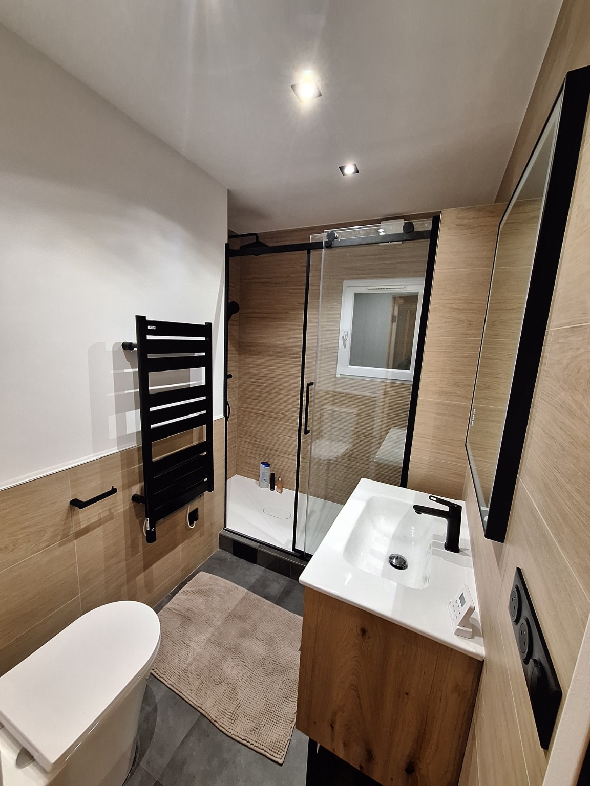 Salle de bains compacte avec meuble en bois et douche