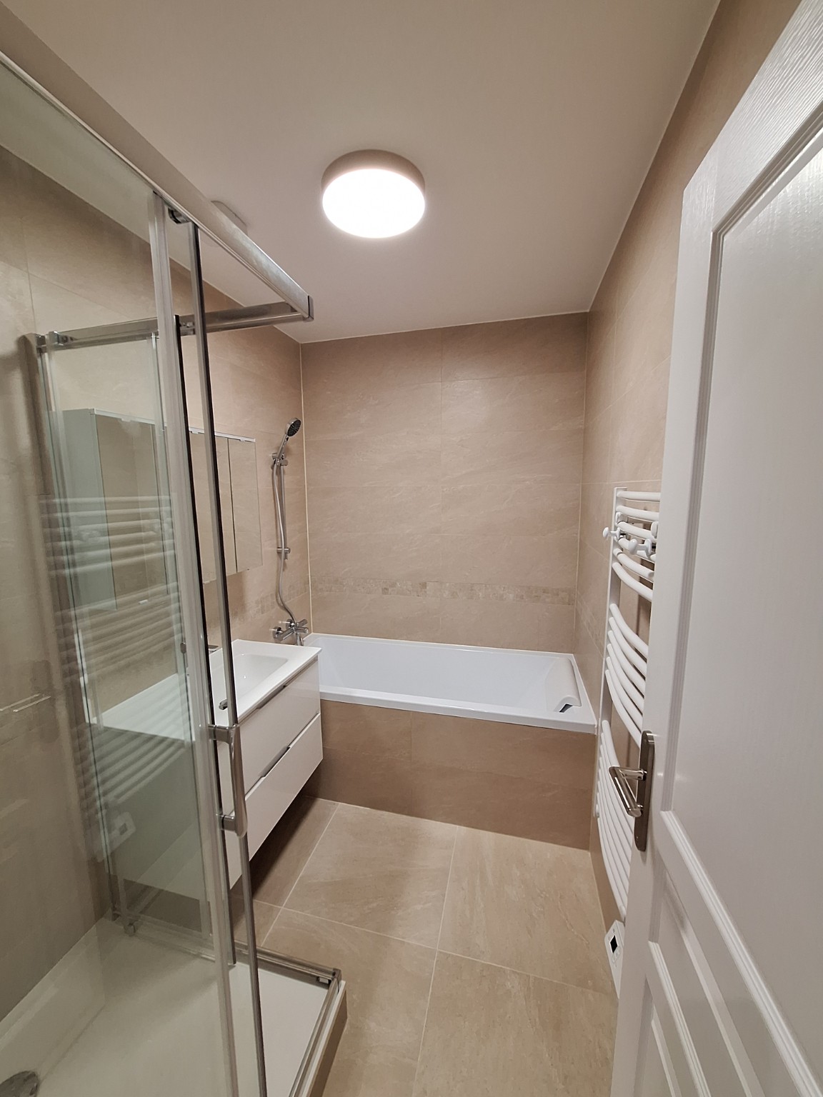 Salle de bains beige avec baignoire et douche vitrée